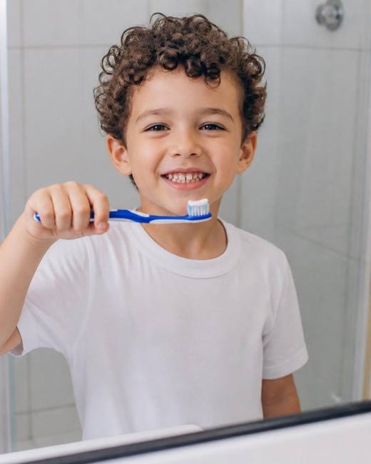 Criança sorrindo enquanto escova os dentes